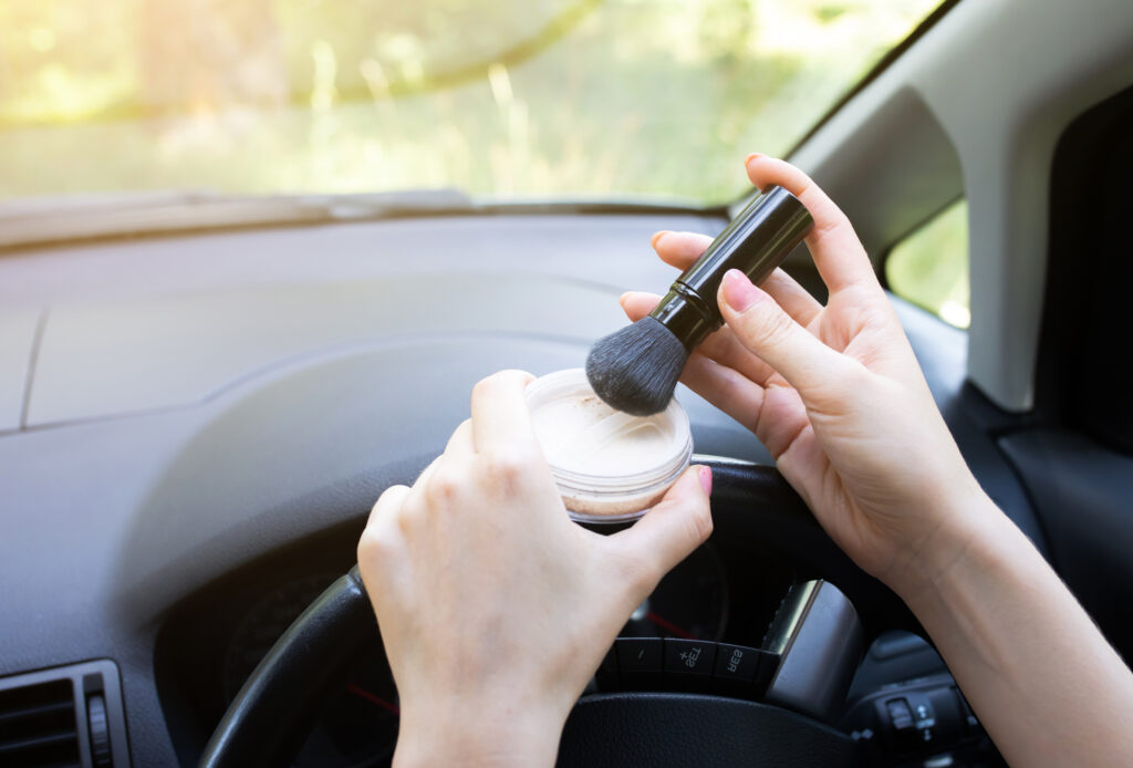 young drivers applying makeup behind the wheel